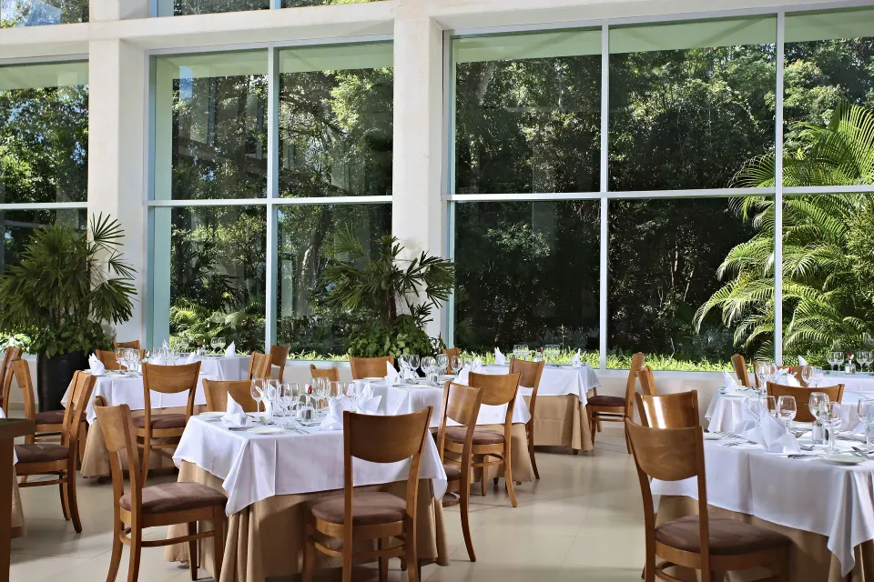 Bright indoor dining room with set tables and large windows at Bahia Principe Luxury Sian Ka'an
