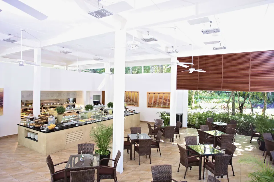 Open buffet dining area with white pillars and wicker tables at Bahia Principe Luxury Sian Ka'an