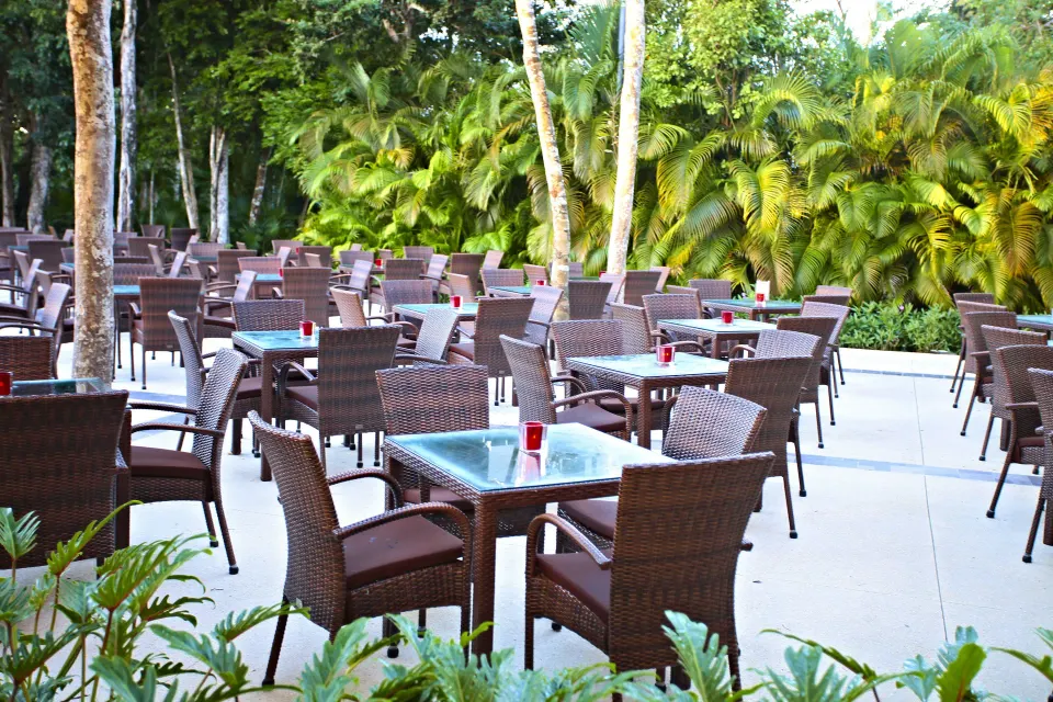 Outdoor patio dining tables surrounded by tropical plants at Bahia Principe Luxury Sian Ka'an