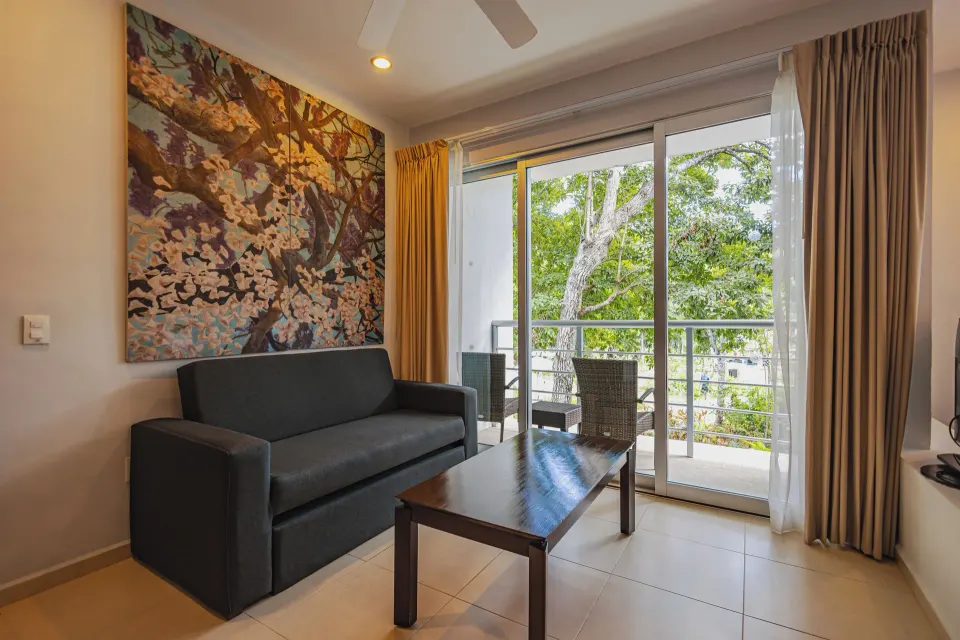 Junior Suite seating area with sofa and balcony doors at Bahia Principe Luxury Sian Ka'an