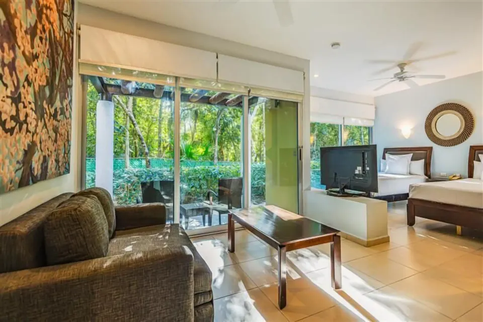 Junior Suite living area with sliding glass doors and patio at Bahia Principe Luxury Sian Ka'an