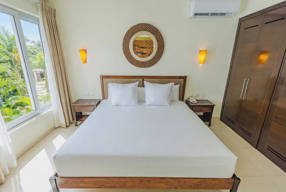 Junior Suite king bed framed by wardrobe and window at Bahia Principe Luxury Sian Ka'an