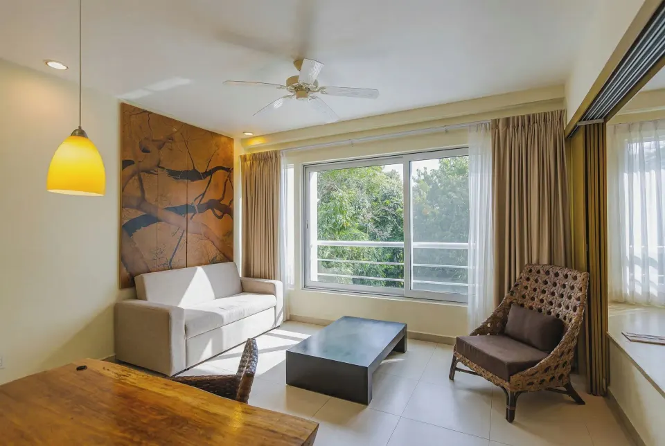 Junior Suite seating area with sofa, chair and large window at Bahia Principe Luxury Sian Ka'an