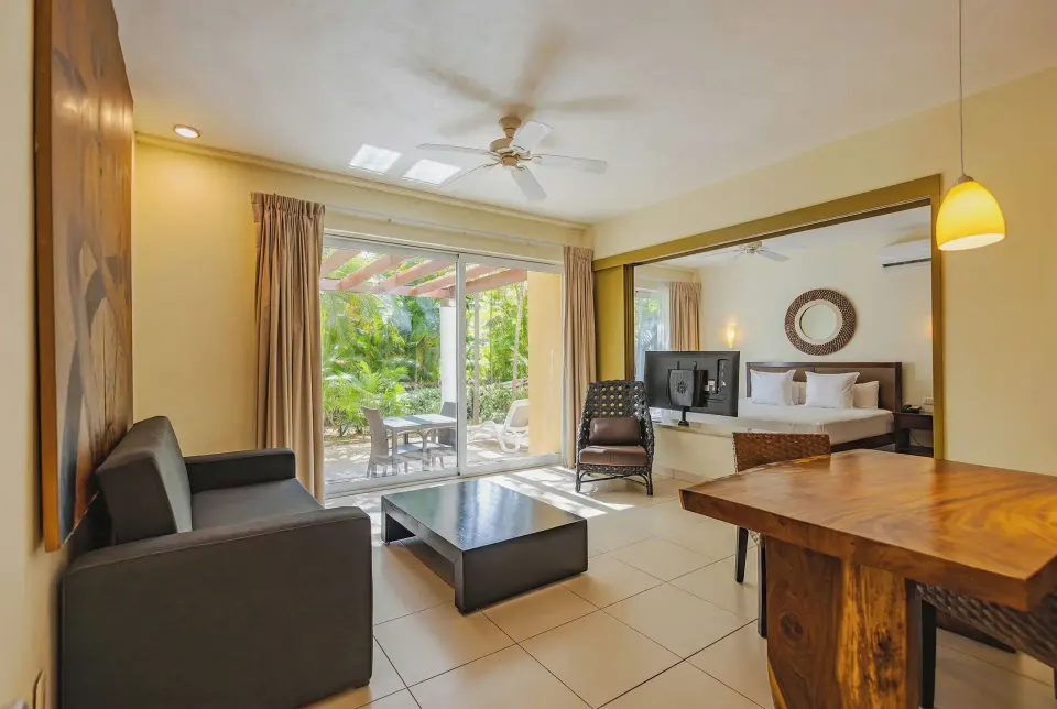 Suite living area with sofa, dining table and sliding doors to the garden at Bahia Principe Luxury Sian Ka'an