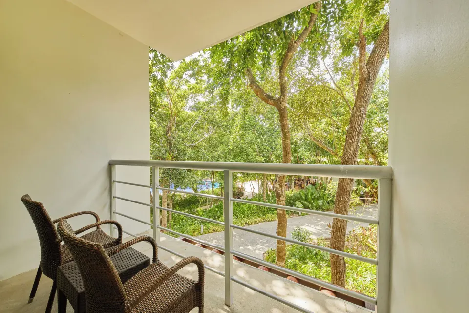 Balcony with two wicker chairs and leafy treetop view at Bahia Principe Luxury Sian Ka'an