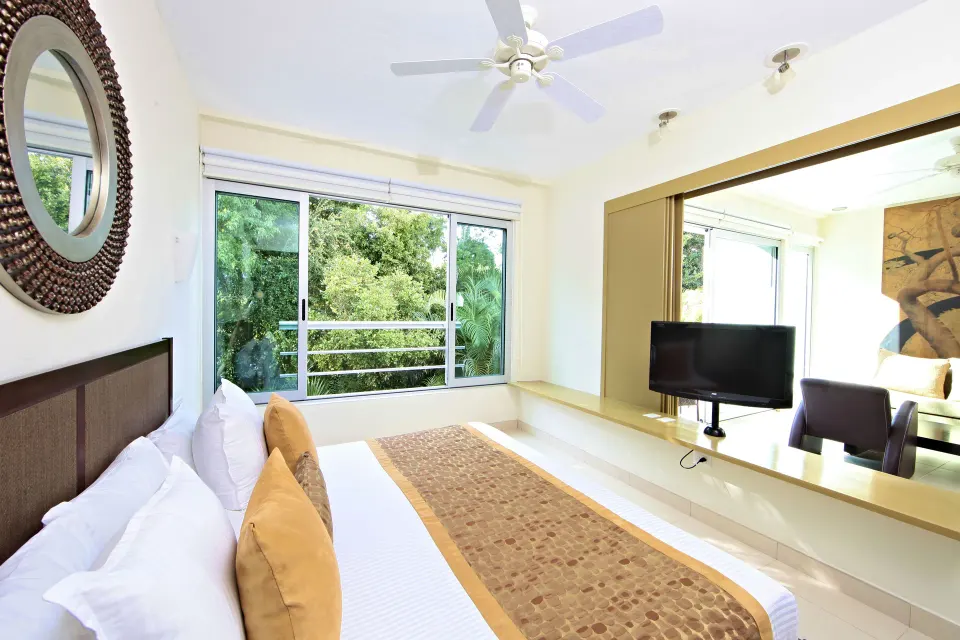 King bed beside a large window with garden views at Bahia Principe Luxury Sian Ka'an
