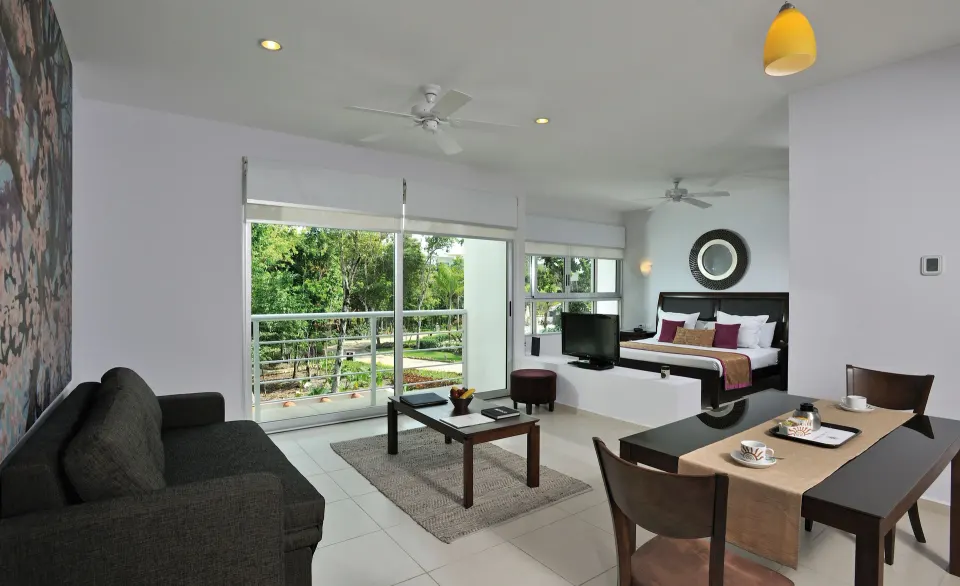 Spacious suite with dining table, sofa and king bed at Bahia Principe Luxury Sian Ka'an