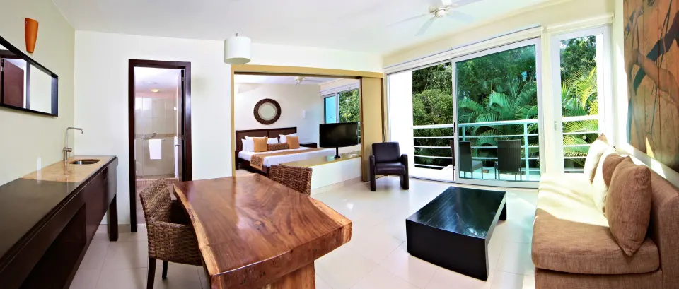 Panoramic Superior Suite view showing dining table, sofa, king bed and balcony at Bahia Principe Luxury Sian Ka'an