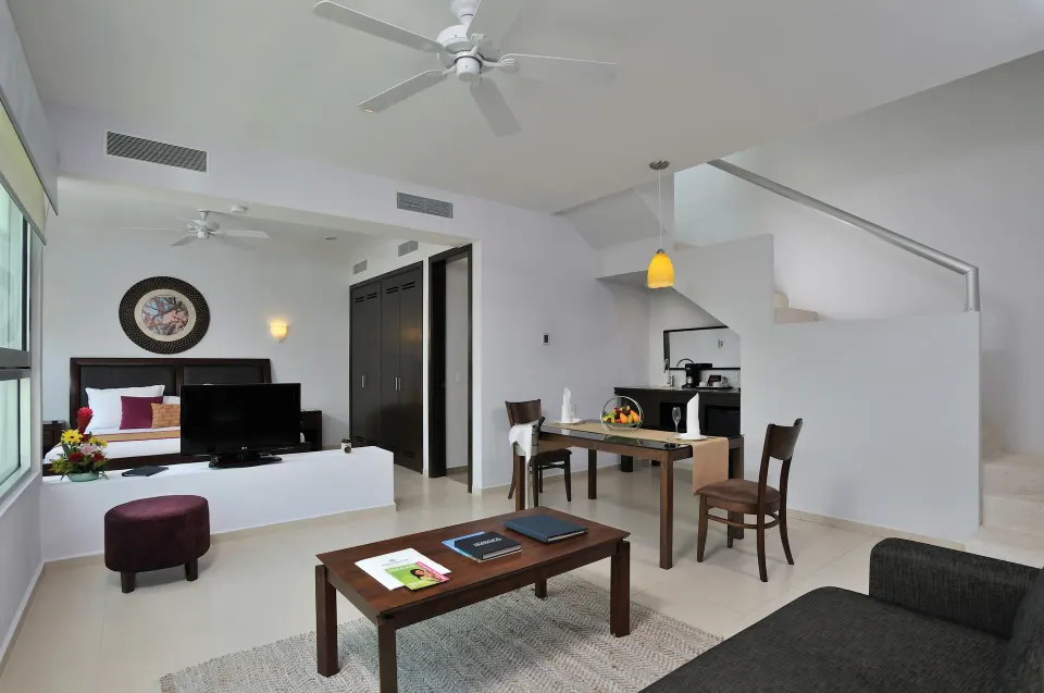 Bright Superior Suite interior with seating area, dining table and king bed at Bahia Principe Luxury Sian Ka'an