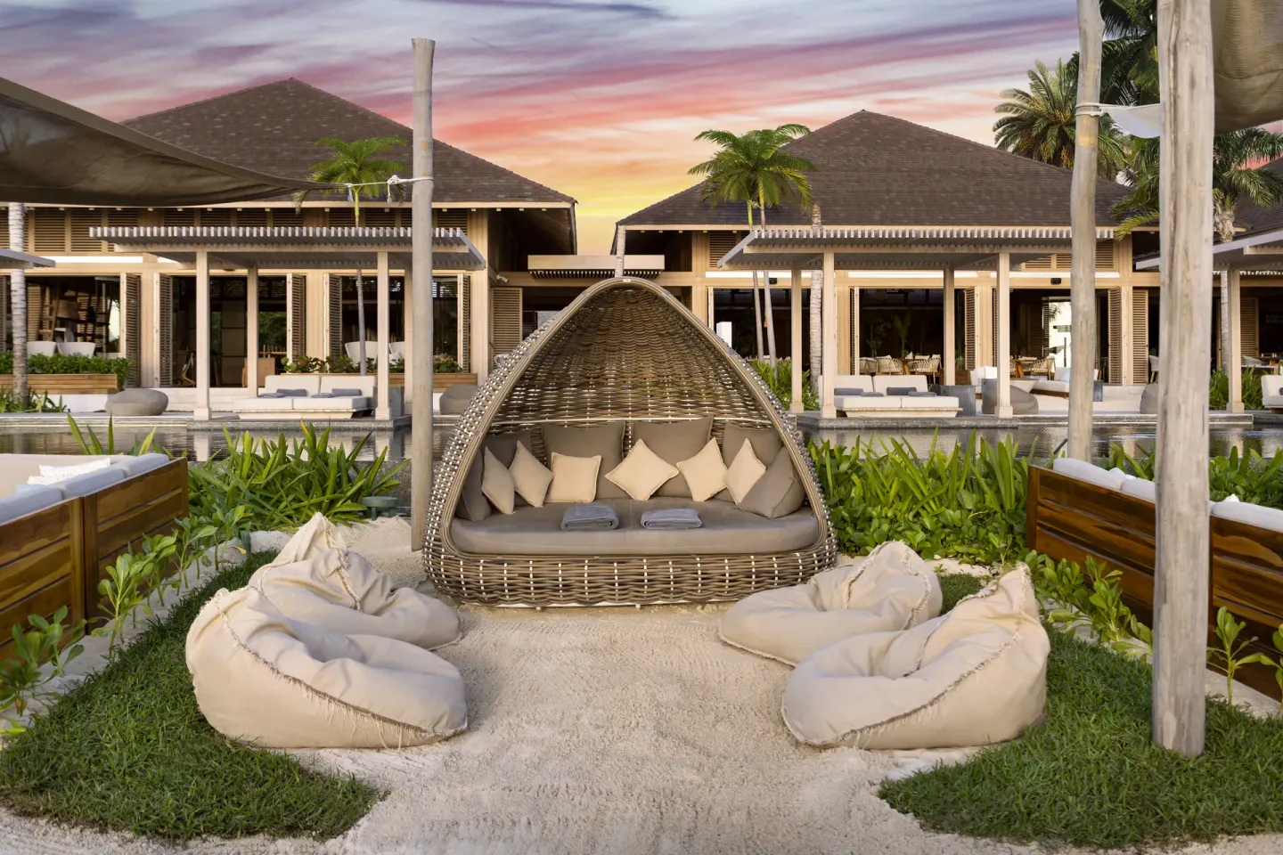 Beach lounge area with cushioned daybed and beanbags at sunset at Banyan Tree Mayakoba.