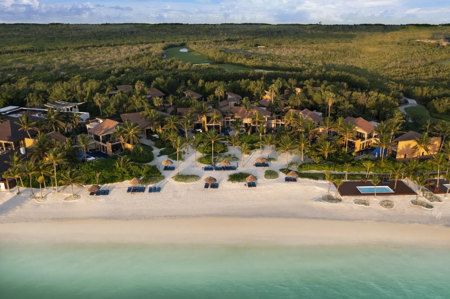 Aerial view of the beach, palms, loungers, and resort buildings at Banyan Tree Mayakoba.
