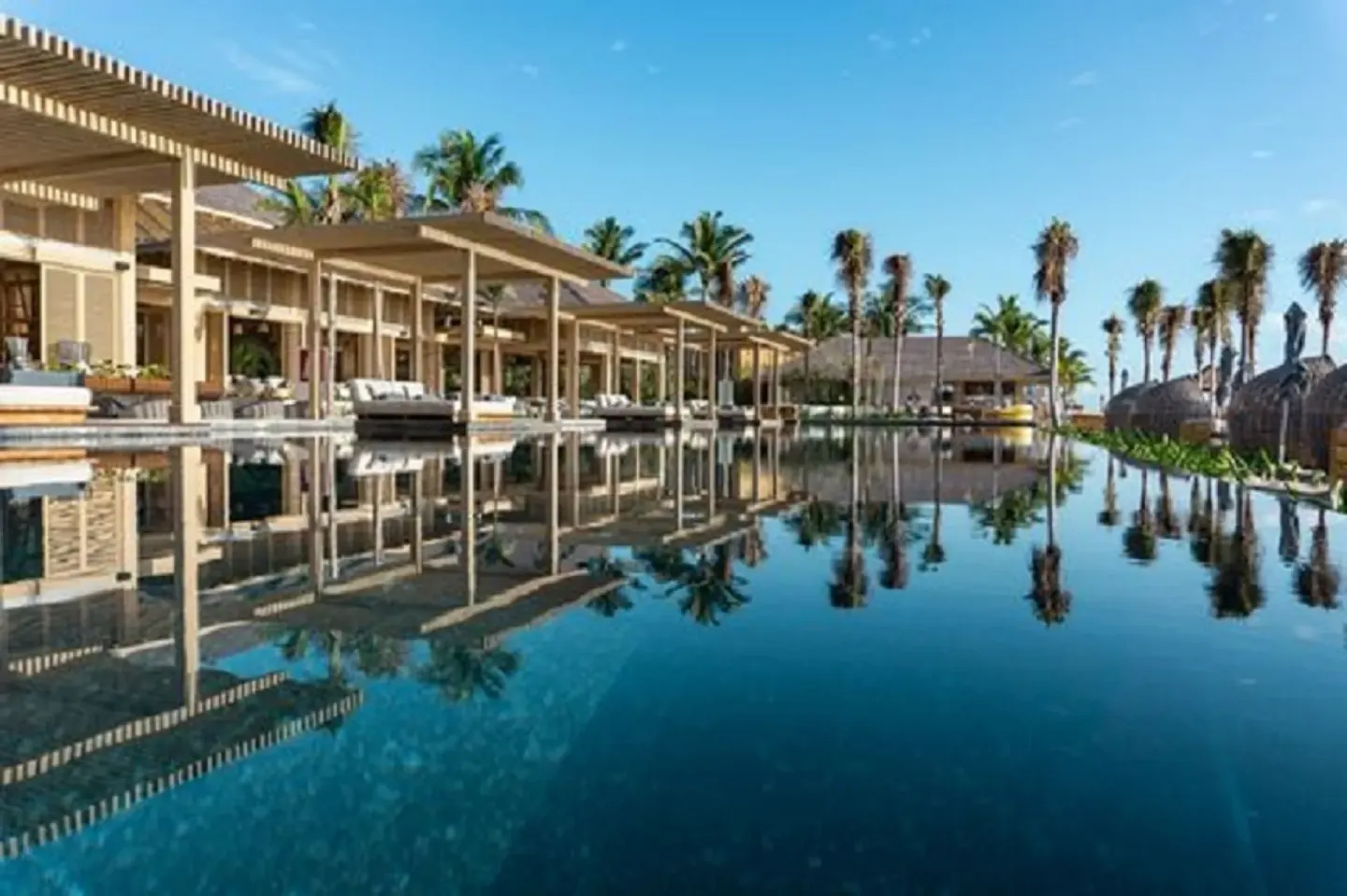 Beachfront pool with palm reflections and cabanas at Banyan Tree Mayakoba.