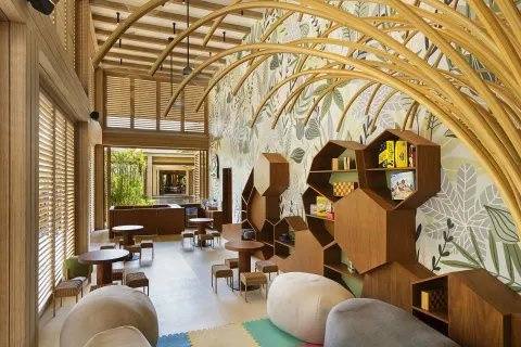 A children’s playroom with tables, shelves, and leaf-patterned walls at Banyan Tree Mayakoba.