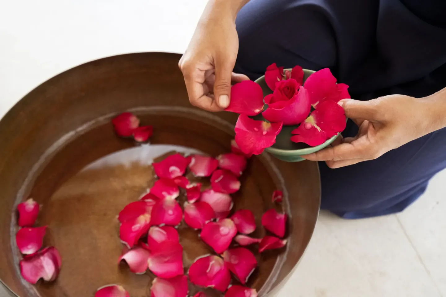 Hands placing red flower petals into a water bowl at Banyan Tree Mayakoba.