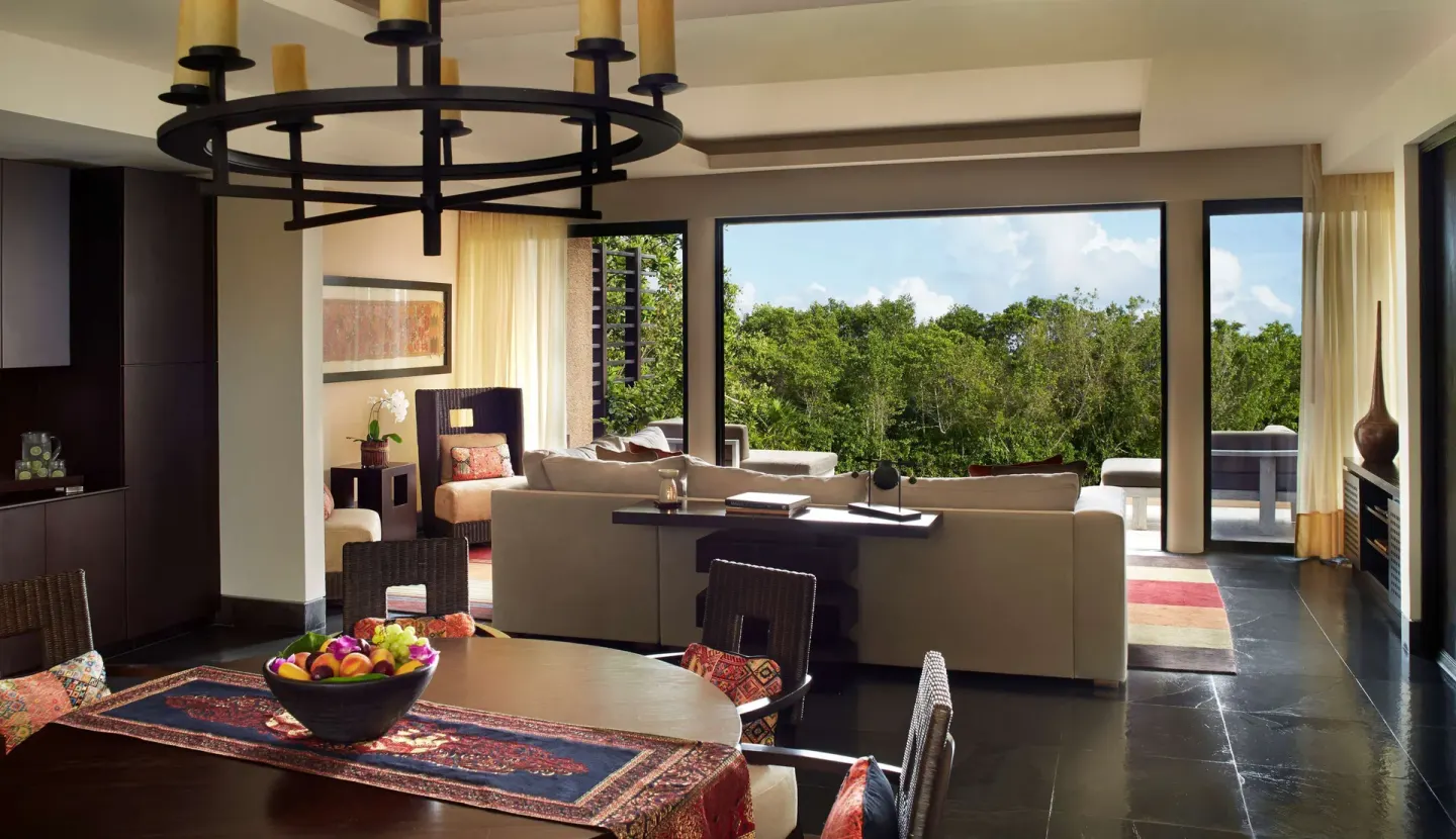 Suite dining and living space with treetop balcony view at Banyan Tree Mayakoba.