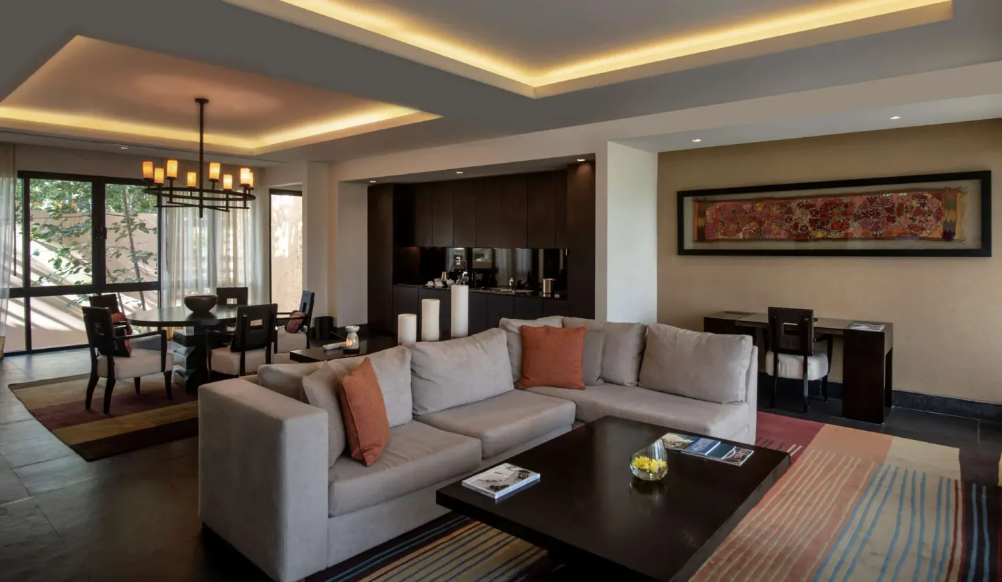 Suite living room with sofa, dining table, and kitchenette at Banyan Tree Mayakoba.