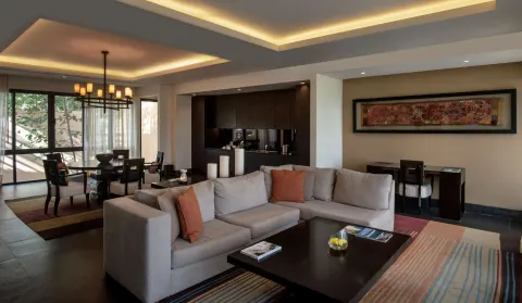 Suite living room with sofa, dining table, and kitchenette at Banyan Tree Mayakoba.