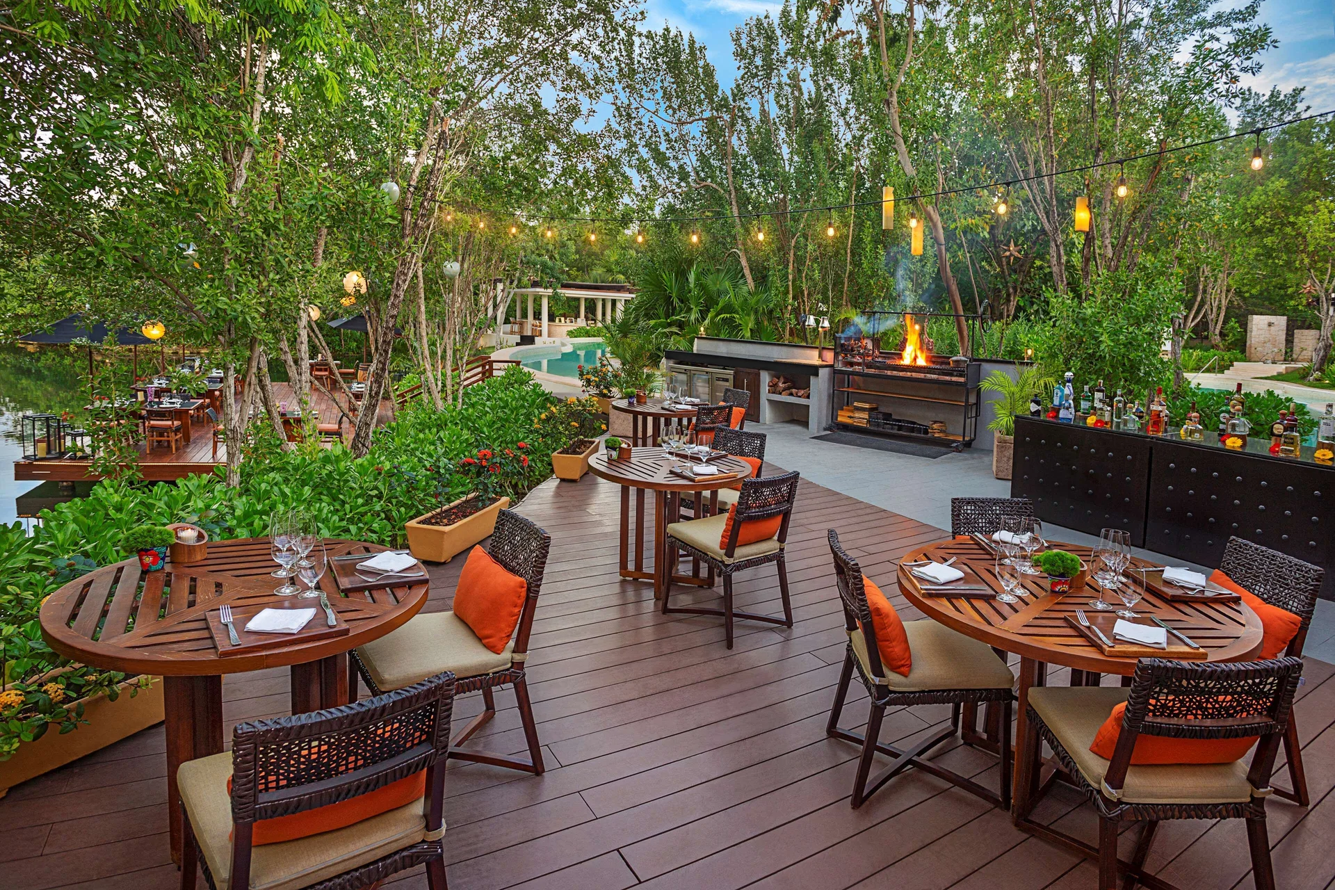 Open-air grill terrace with set tables among trees at Banyan Tree Mayakoba.