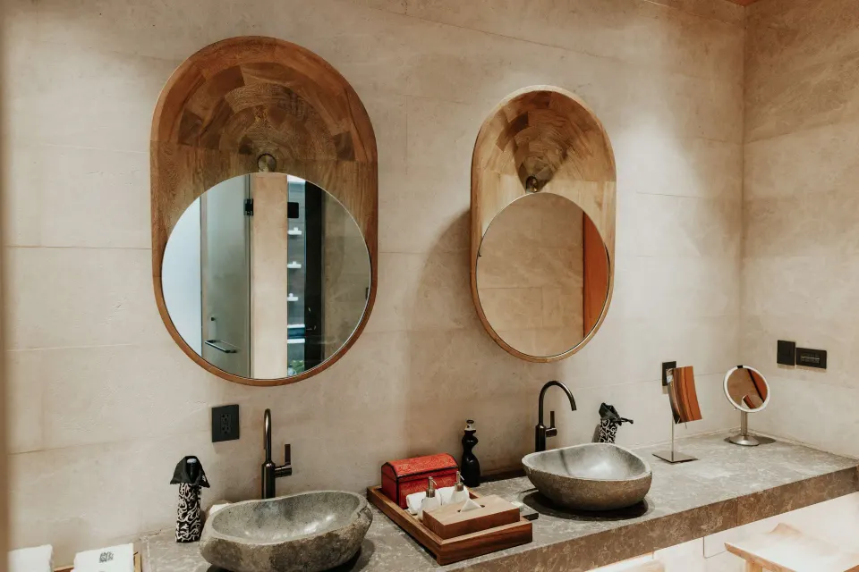 Beachfront Lanai Pool Suite bathroom at Banyan Tree Mayakoba with twin stone sinks and round mirrors.
