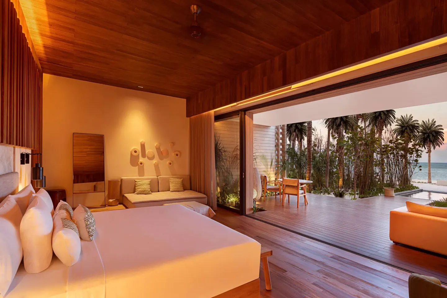 Beachfront Lanai Pool Suite king bed at Banyan Tree Mayakoba opening to a deck and ocean view.