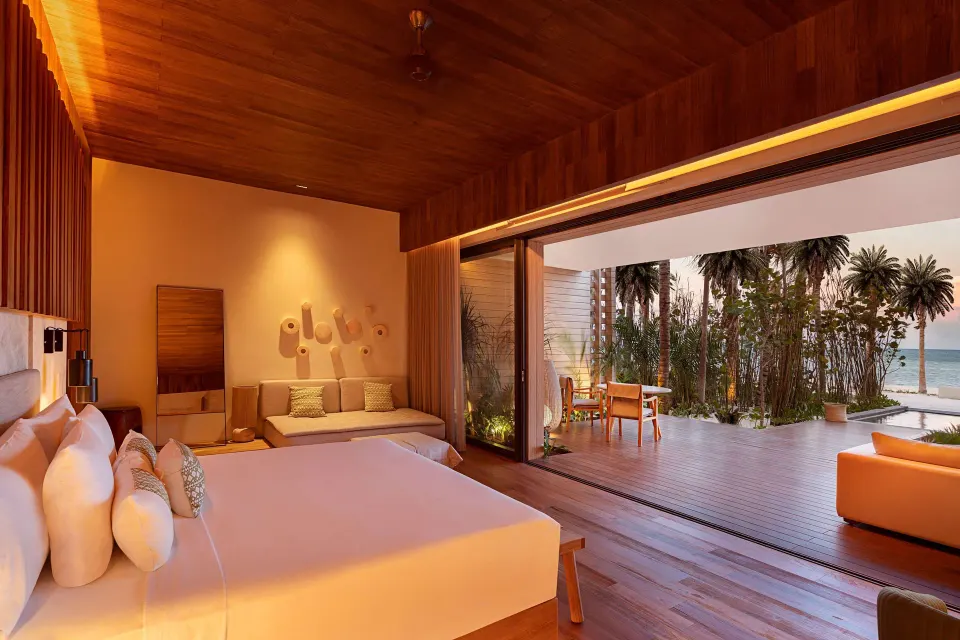Beachfront Lanai Pool Suite king bed at Banyan Tree Mayakoba opening to a deck and ocean view.