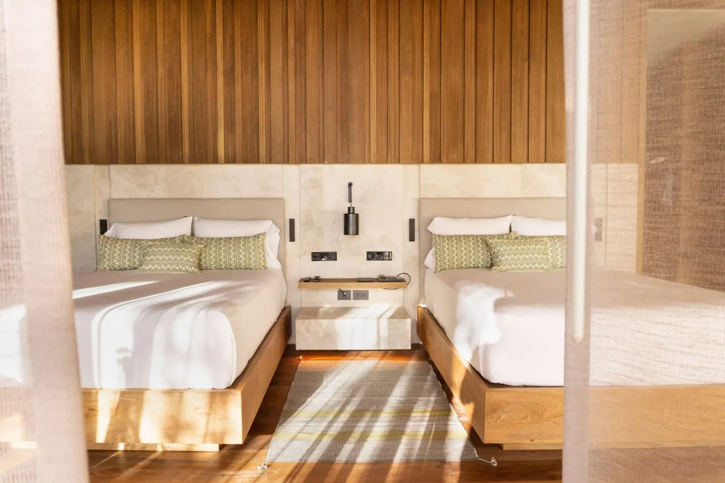 Beachfront Lanai Pool Suite twin beds at Banyan Tree Mayakoba with wood paneling and soft daylight.