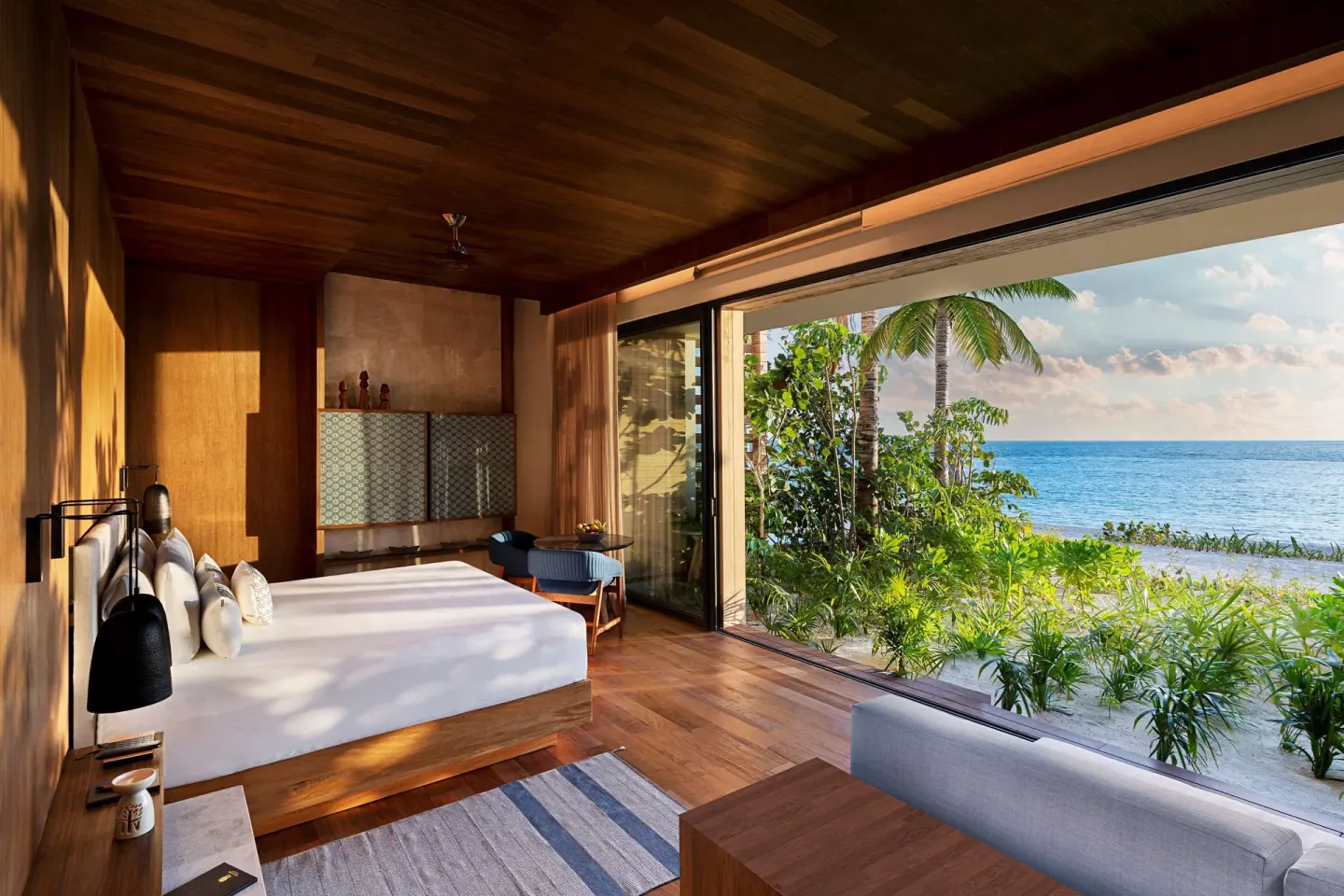 Beachfront Terrace Pool Suite king bed beside ocean-facing glass at Banyan Tree Mayakoba.