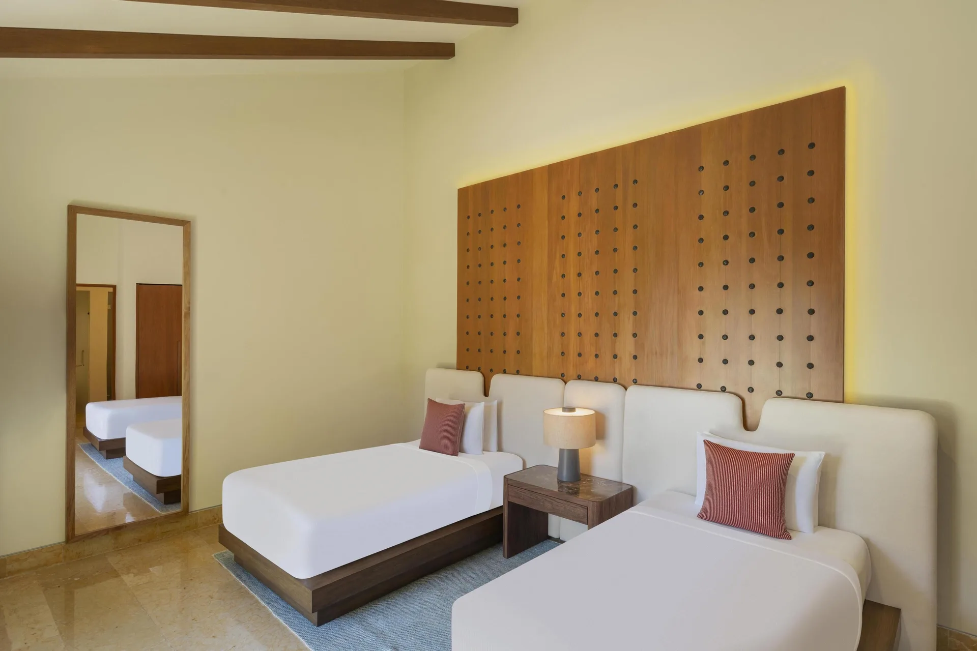 Twin bedroom with wood headboard and full mirror at Banyan Tree Mayakoba.