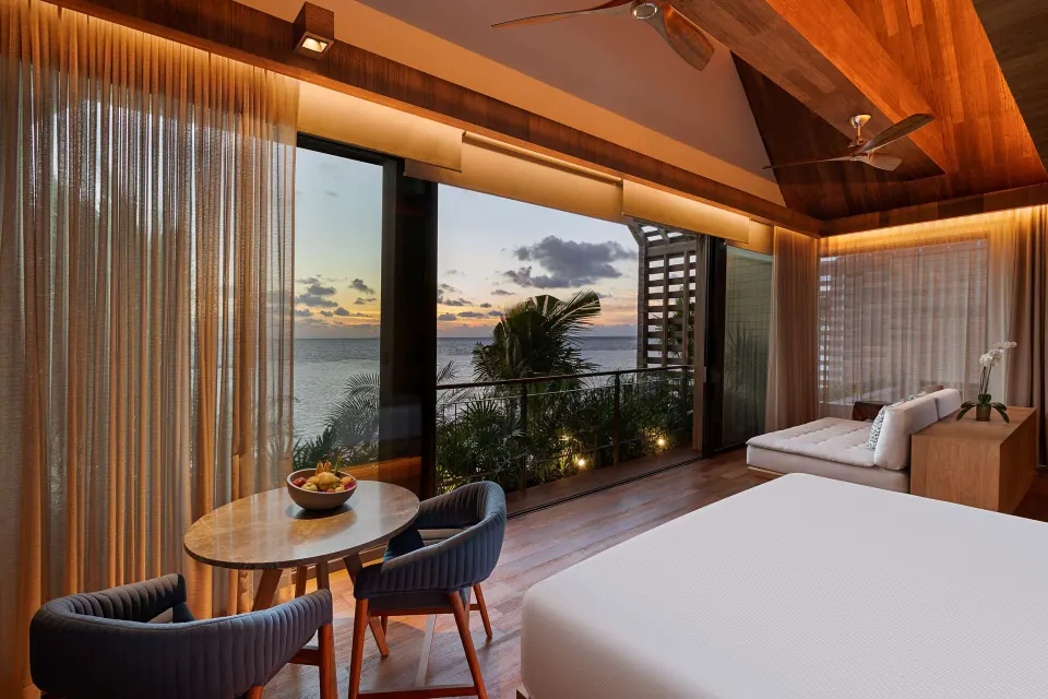 Oceanfront Balcony Pool Suite bedroom at sunset with ocean-facing windows at Banyan Tree Mayakoba.