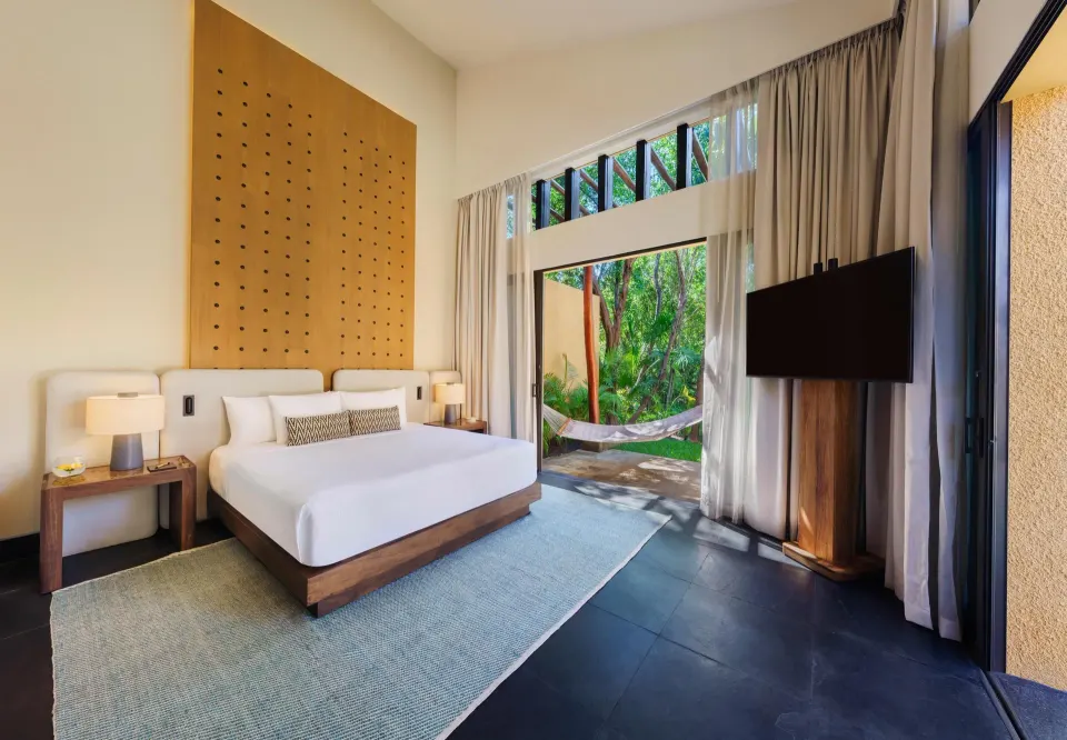 Serenity Pool Villa king bedroom at Banyan Tree Mayakoba with garden-facing glass doors and hammock outside.
