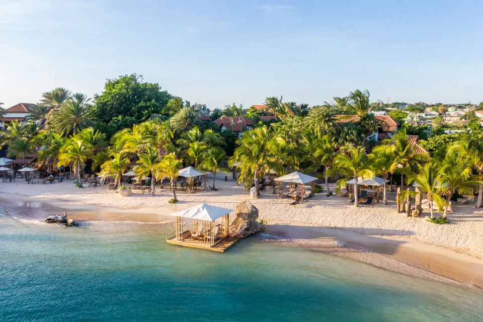 Aerial view of a sandy beachfront lined with palms and cabanas at Baoase Luxury Resort
