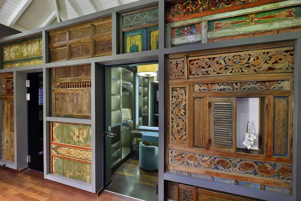 Decorative carved wooden panels and open doorway to a bathroom at Baoase Luxury Resort