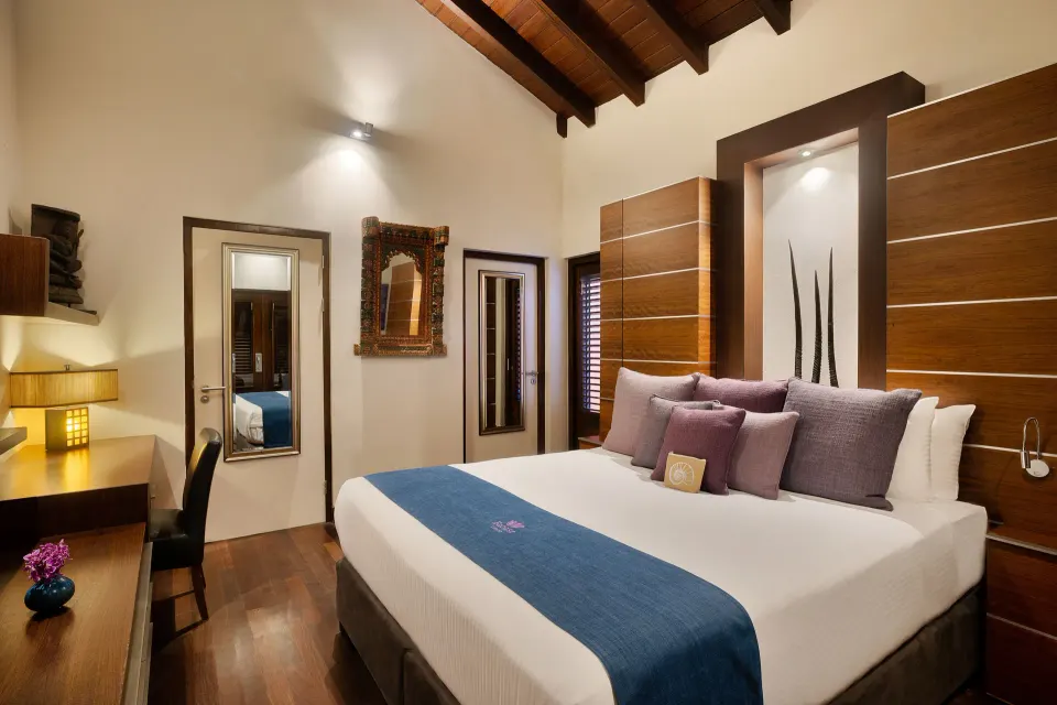 Elegant bedroom with king bed, purple cushions and wood-beamed ceiling at Baoase Luxury Resort.
