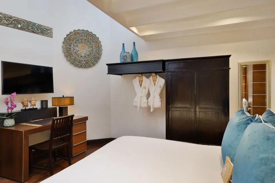 Guest room desk area with wall TV, wardrobe and hanging robes at Baoase Luxury Resort.