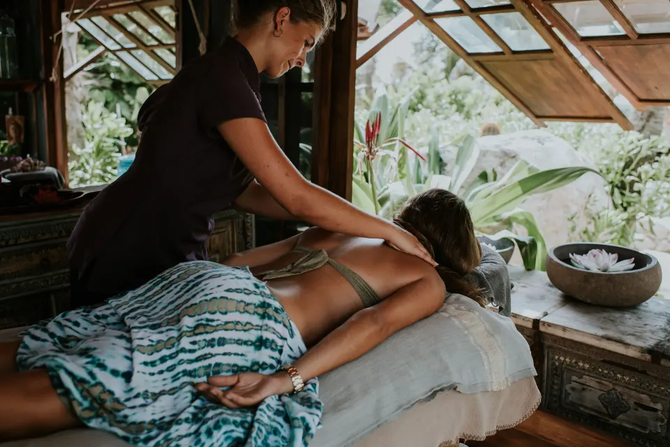 Therapist giving a massage in an open-air spa room at Baoase Luxury Resort.