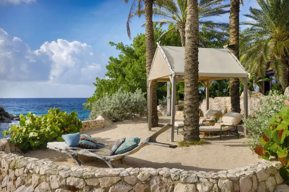 Private beach cabana with lounge chairs and palm trees at Baoase Luxury Resort