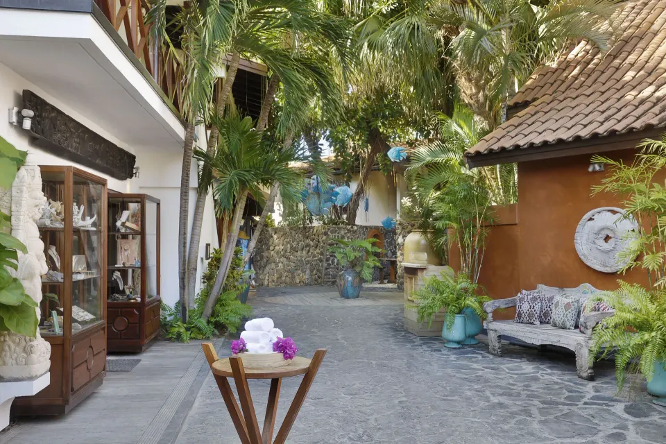 Shaded stone courtyard with seating, plants and display cabinets at Baoase Luxury Resort.