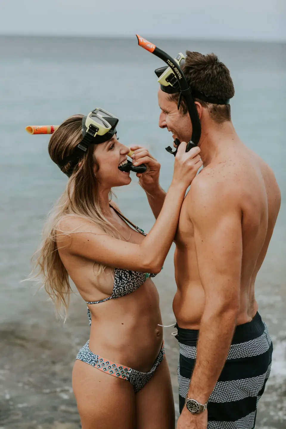 Couple in snorkel gear sharing a playful moment on the beach at Baoase Luxury Resort