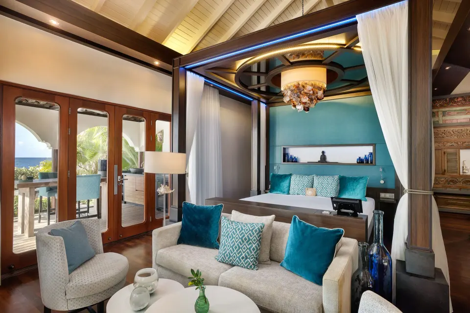 Four-poster bed suite with turquoise accents and balcony doors at Baoase Luxury Resort