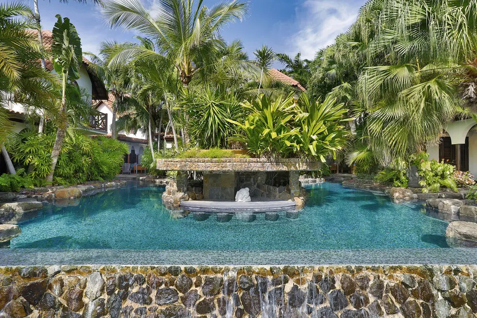 Resort pool surrounded by tropical plants and stone features at Baoase Luxury Resort