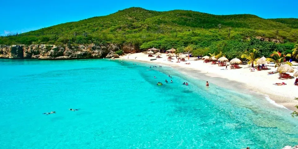 Turquoise bay with white sand beach and thatched umbrellas at Baoase Luxury Resort.