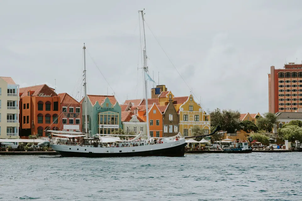 Colorful waterfront buildings and a sailing ship seen from the water at Baoase Luxury Resort.