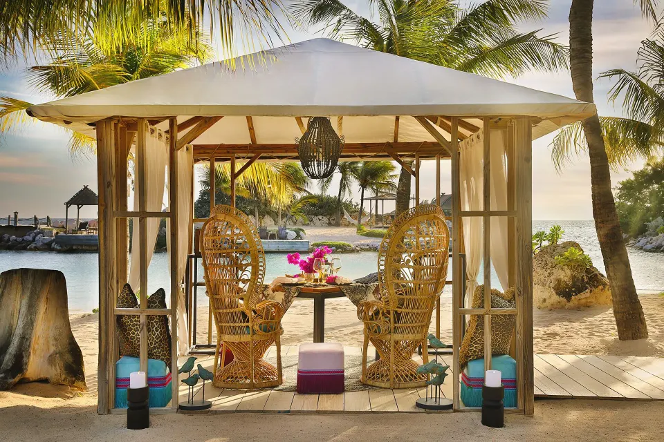 Private beach gazebo with wicker chairs and table at Baoase Luxury Resort