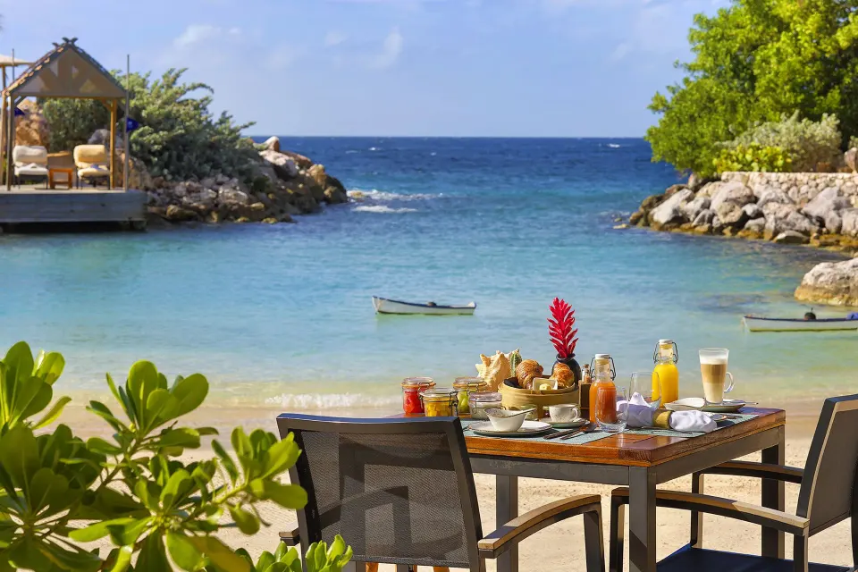 Breakfast spread on a table on the sand with lagoon view at Baoase Luxury Resort