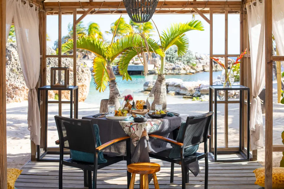 A private beach dining table set under a cabana at Baoase Luxury Resort.