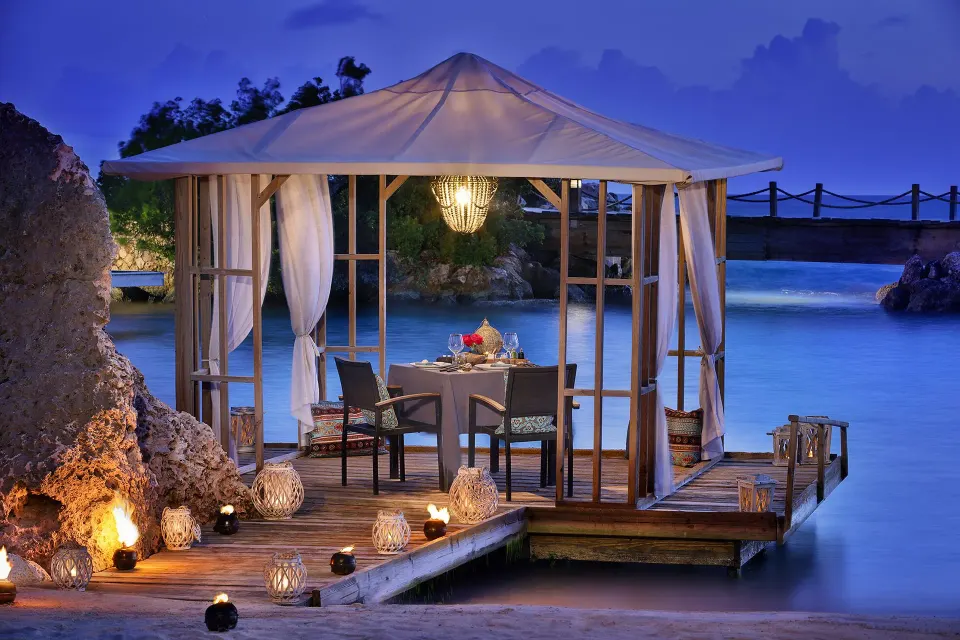 Overwater dining gazebo lit at dusk at Baoase Luxury Resort