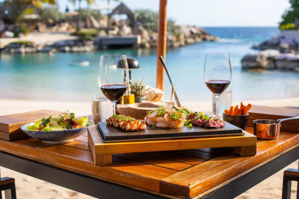 Lunch boards and red wine on a table by the lagoon at Baoase Luxury Resort