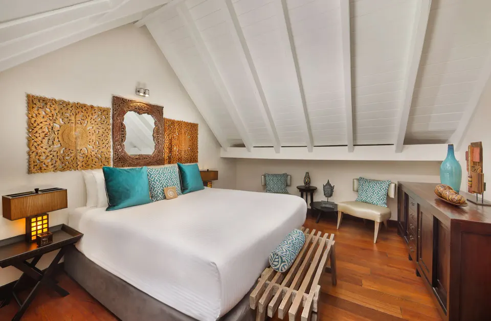 Loft Room king bed with carved wooden headboard and teal cushions at Baoase Luxury Resort