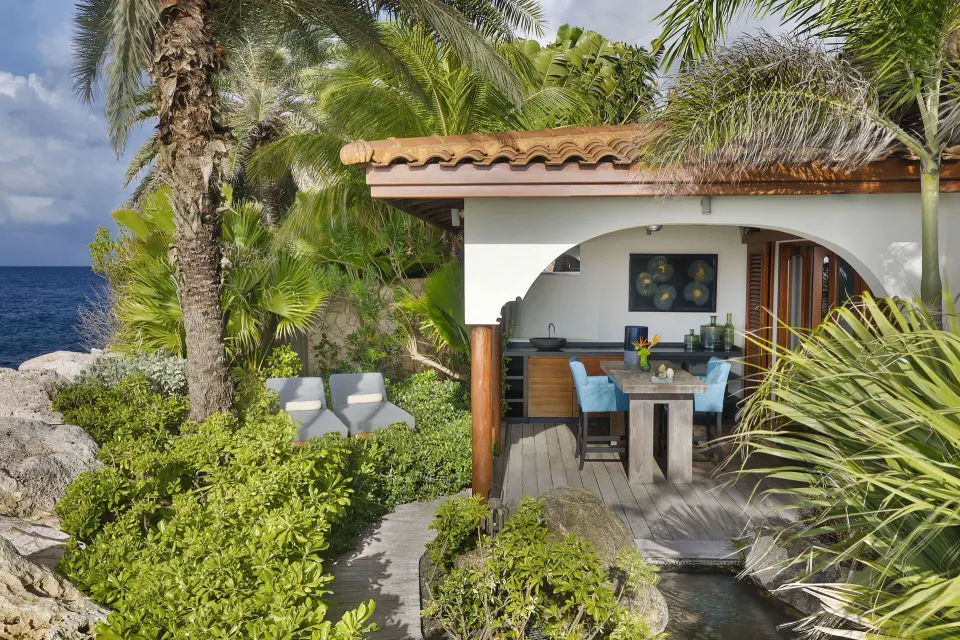Covered outdoor dining terrace and garden steps beside the sea at Baoase Luxury Resort