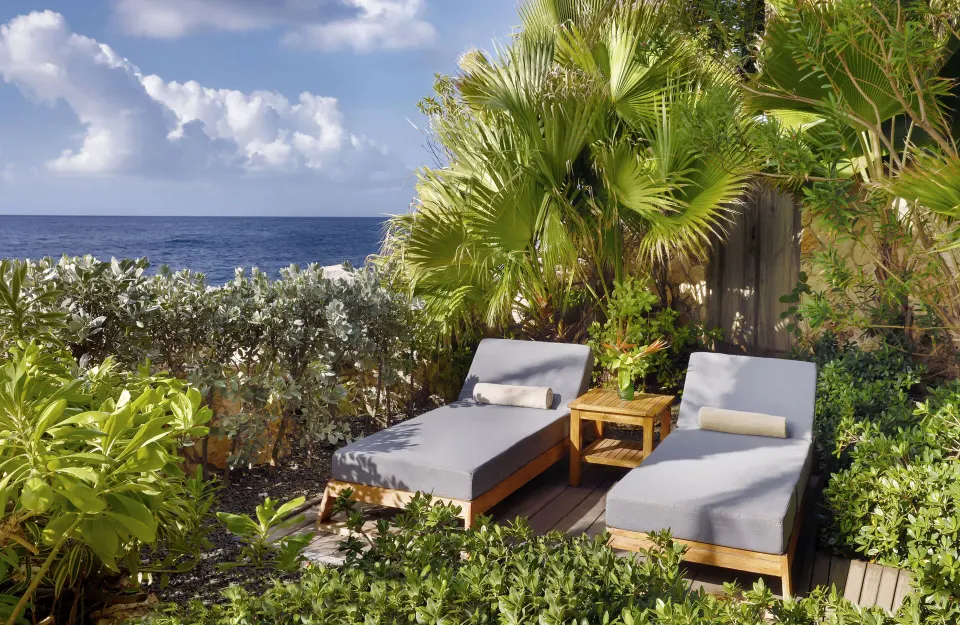 Two lounge chairs set among tropical plants with an ocean view at Baoase Luxury Resort
